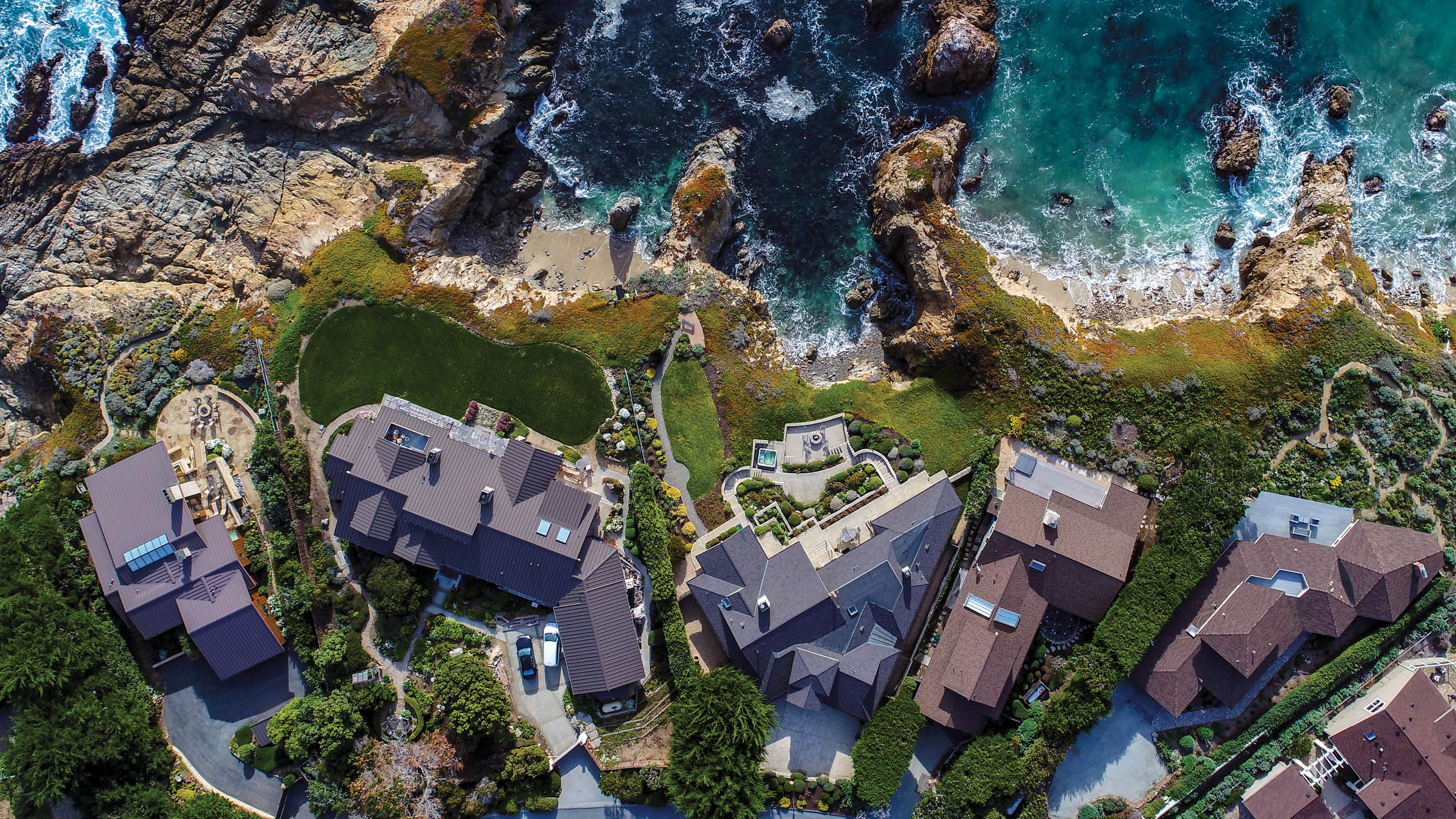 An aerial image of houses along a rocky coastline